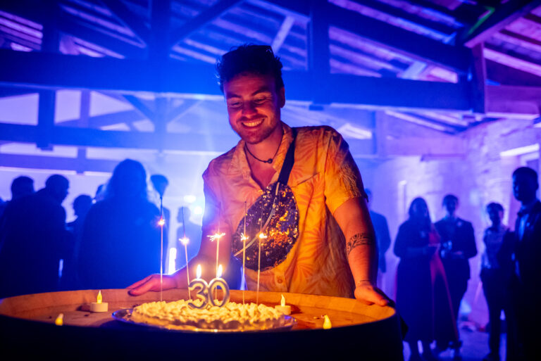Invité souriant devant son gâteau de 30 ans pendant une soirée colorée