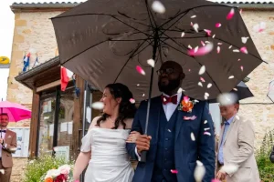 Mariés sous un parapluie entourés de pétales roses et blancs