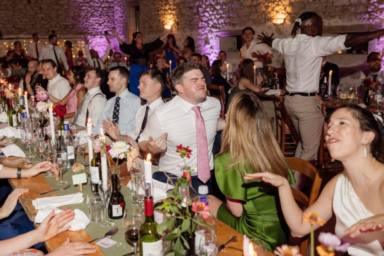 Grande tablée de mariage éclairée aux bougies, les invités rient pendant le repas