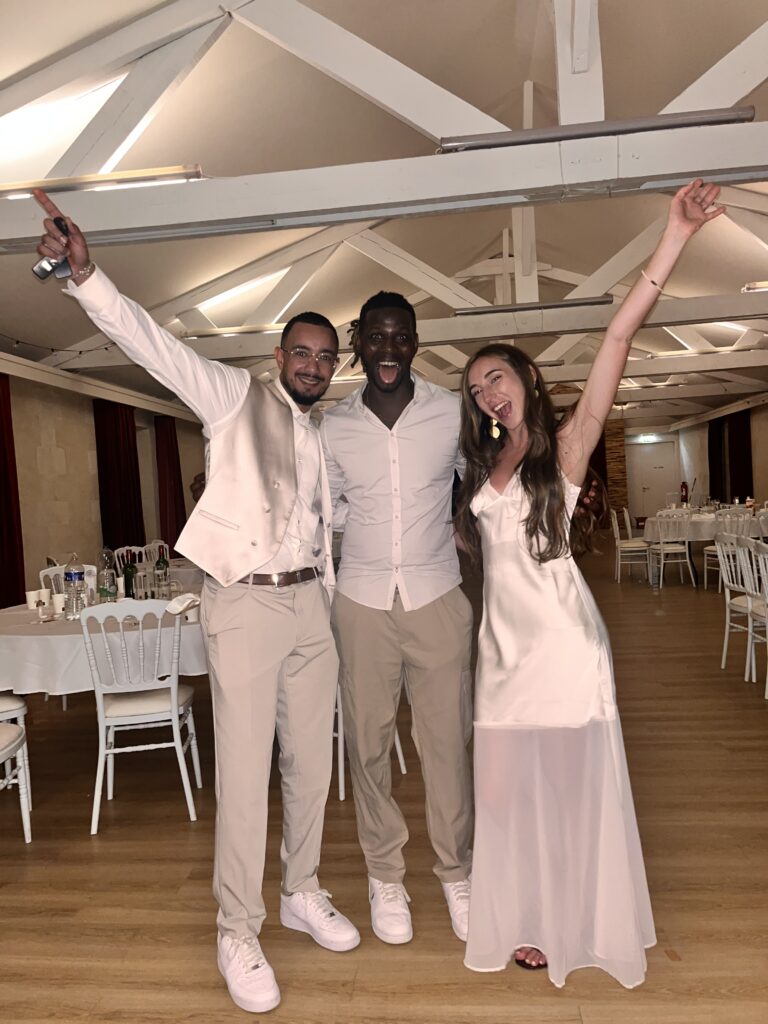 DJ Lexvolution avec les mariés, bras levés, à la fin de la soirée dans une salle de réception