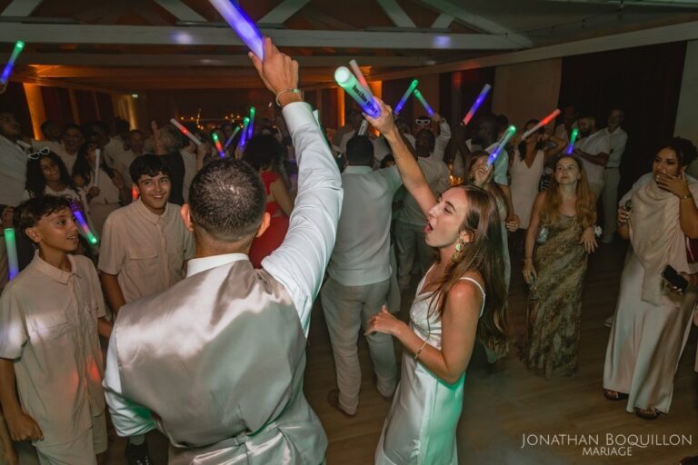 Invités sur la piste avec des bâtons lumineux levés pendant le dancefloor