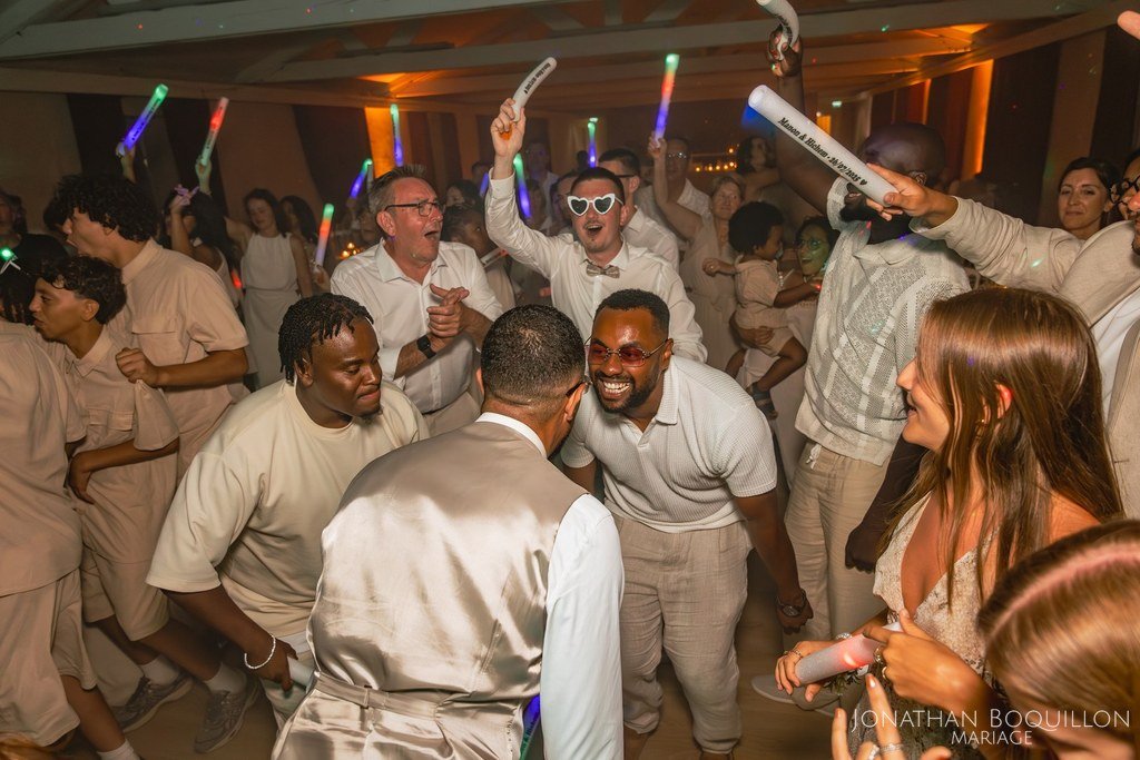 Invités de tous âges en train de danser avec des bâtons lumineux personnalisés au nom des mariés