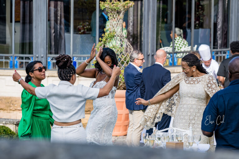 Invités et mariée pendant une cérémonie en extérieur, tenues colorées et arche fleurie