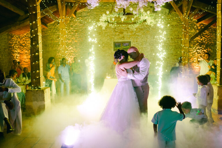 Première danse des mariés sous la fumée lourde et les lumières vertes, entourés de leurs invités