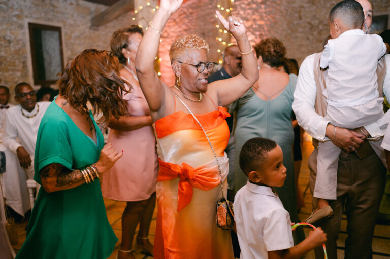 Invités les bras levés sur la piste de danse d'une grange en pierre lors d'un mariage