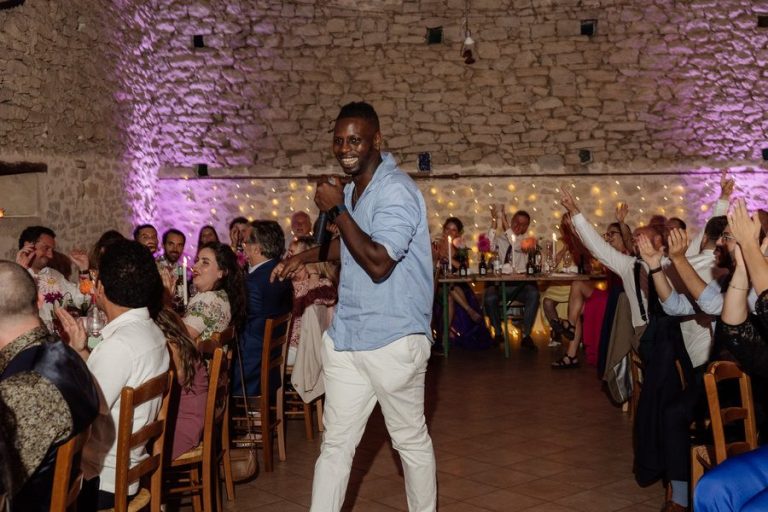 DJ Lexvolution au micro pendant un anniversaire, invités attablés qui applaudissent