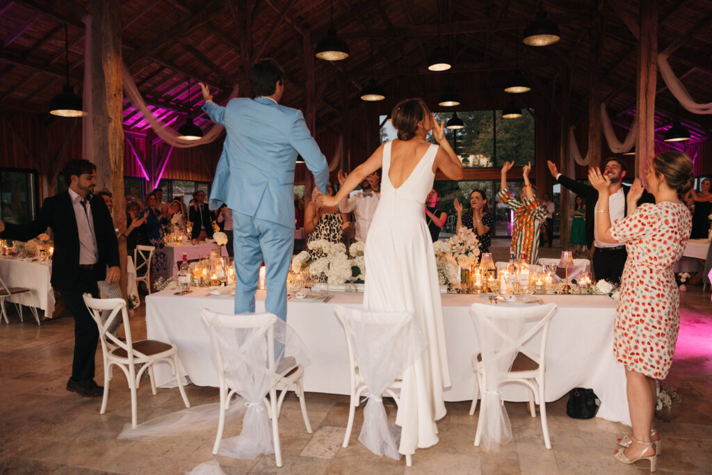Les mariés debout sur leurs chaises, entourés de leurs invités en fête